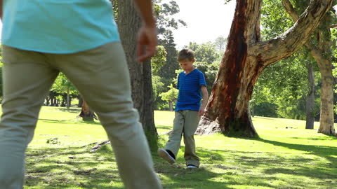 Boy Walking Through Sunny Park with Parent in Summer