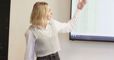 Businesswoman presenting financial data on office screen