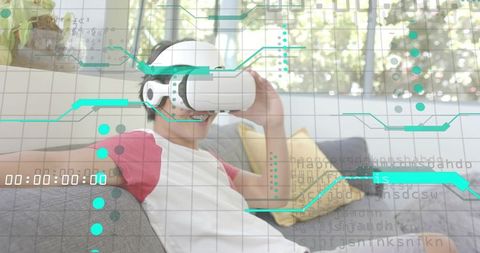Asian Man Relaxing on Sofa Wearing VR Headset Interacting with Futuristic HUD Interface