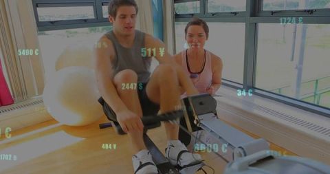 Personal trainer motivating client on indoor rowing machine