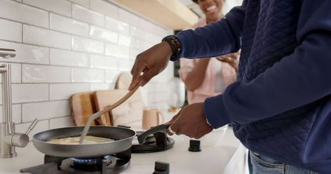 Couple Cooking Together Using Stove and Utensils