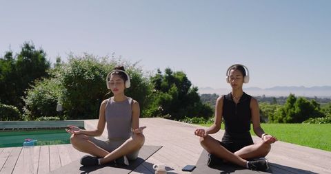 Women meditating with headphones outdoors