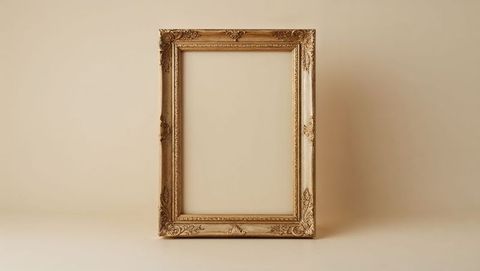 Ornate golden picture frame with antique carved motifs empty on table