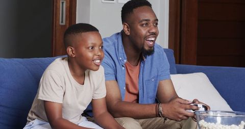Father and son bonding over video games on comfortable sofa