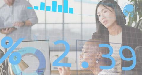 Reviewing team analyzing data dashboards with translucent analytics overlay in office