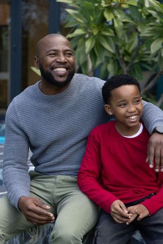 African american father sharing laugh with son on patio, showing warm family bond and love