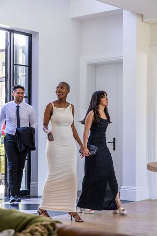 Diverse friends entering modern foyer wearing elegant evening gowns and suit