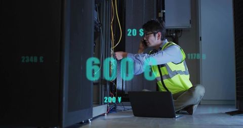 Data center technician fixing rack cables while calling and monitoring analytics on laptop