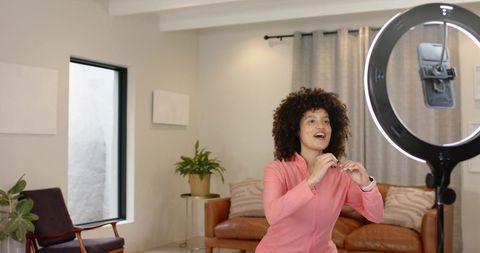 Young woman recording lifestyle vlog with ring light in stylish living room home studio