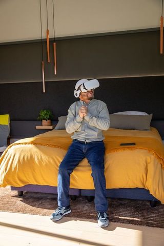 Senior asian man wearing vr headset on bed enjoying virtual reality at home