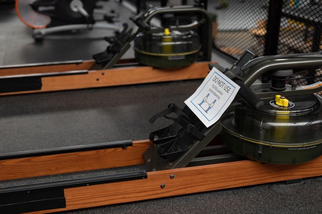 Rowing machine in a gym with a do not use sign for social distancing. Useful for articles or advertisements about gym safety measures, social distancing practices, and maintaining health and safety in fitness centers during the pandemic.