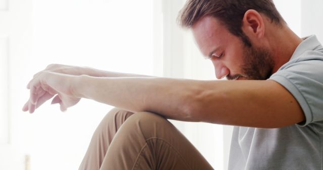 Man in Thoughtful Pose Seated with Head Down in Bright Room - Download Free Stock Images Pikwizard.com