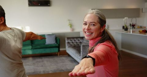 Smiling woman practicing warrior ii pose in stylish living room