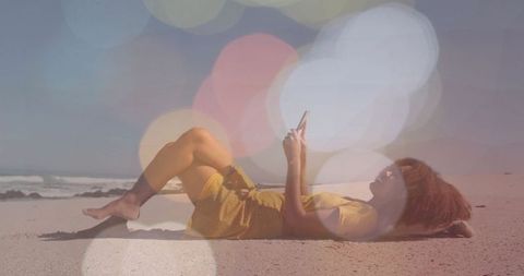 Woman Relaxing on Beach with Smartphone and Bokeh Lights Overlay
