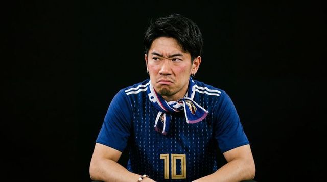 Frowning asian soccer fan wearing number 10 jersey and scarf showing stern intensity