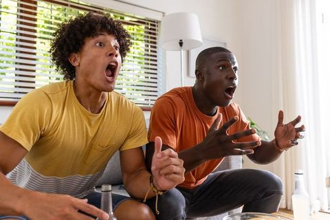 Diverse Male Friends Reacting Intensely on Couch at Home