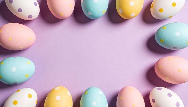 Pastel polka dot easter eggs forming oval frame on lavender background with copy space