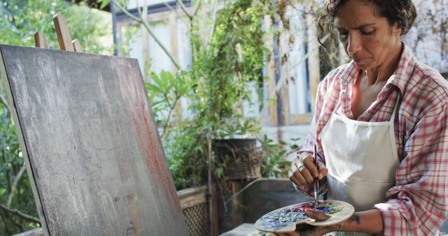 Focused Artist Mixing Paint Outdoors in Sunlit Garden - Download Free Stock Images Pikwizard.com