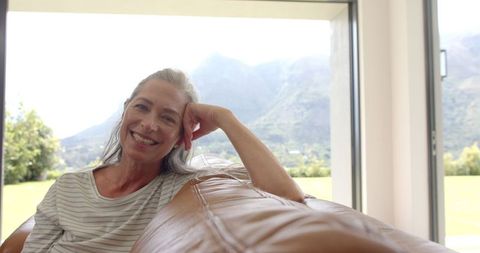 Mature Woman Relaxing on Couch Smiling with Mountains in Background