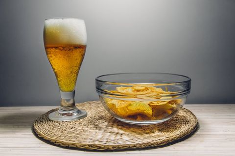 Refreshing beer with glass bowl of crispy chips on a woven placemat