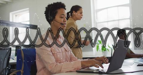 Customer support agent typing on laptop wearing headset in sunlit open office with waveform overlay