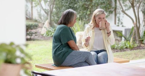 Senior women enjoying coffee in tranquil garden patio