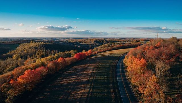 Winding country road curving through autumn fields with vibrant fall foliage