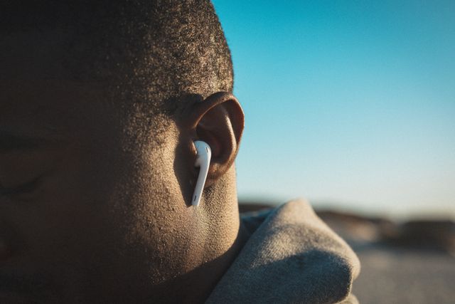 Close up of african american man exercising, wearing headphones on beach at sunset. healthy outdoor lifestyle fitness training.