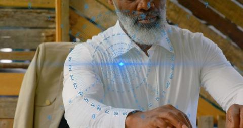 Senior man placing hands on wooden table viewing blue augmented reality hud in rustic loft