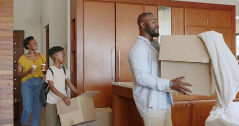 African American family moving into new home carrying boxes and unpacking in kitchen