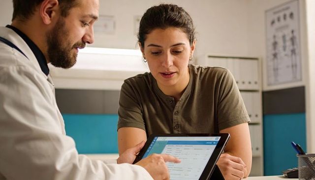 Clinician explaining electronic health record on tablet during patient consultation