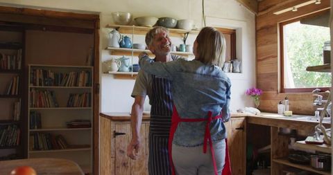 Senior Couple Dancing Joyfully in Rustic Kitchen Before Cooking