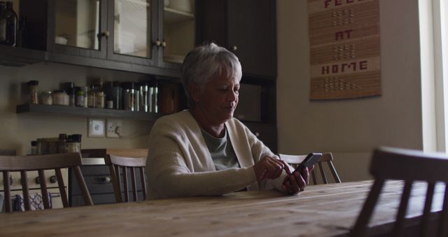 Elderly Woman Using Smartphone at Home Kitchen Table - Download Free Stock Images Pikwizard.com