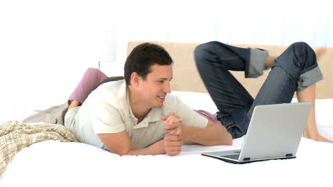 Couple Enjoying Leisure Time with Laptop on Bed