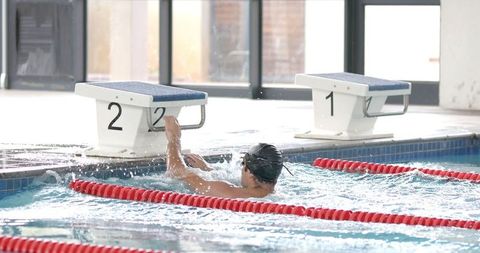 Competitive swimmer training near starting blocks in indoor pool