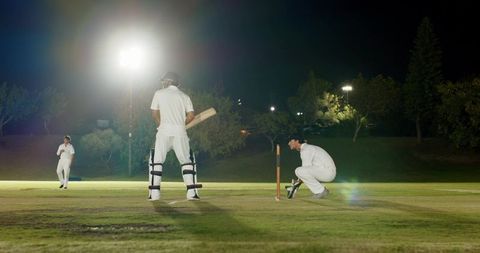 Night cricket match under floodlights with indian batsman at crease and wicketkeeper