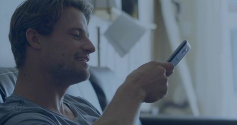 Mid-Adult Man Relaxing on Sofa Holding Remote Watching TV in Cozy Modern Living Room Home