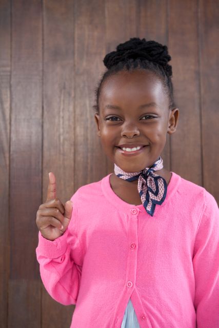 Smiling Young Girl Pointing Upward in Pink Cardigan - Download Free Stock Photos Pikwizard.com