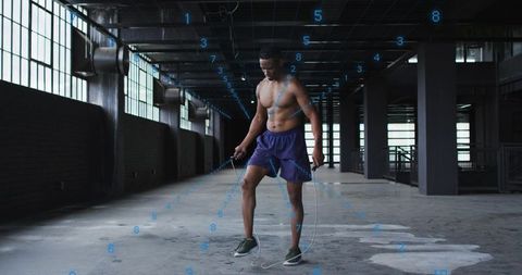 Shirtless athlete skipping rope in industrial warehouse with digital numeric grid overlay