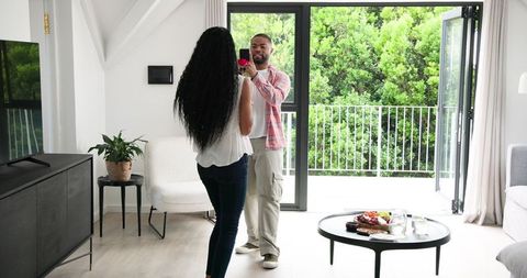 Man Offering Rose to Woman at Home, Romantic Scene by Large Window
