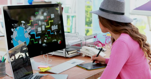 A young Caucasian girl is engaged in digital artwork on a computer, with copy space. Her focus and creativity are evident as she uses a graphics tablet to bring her ideas to life.