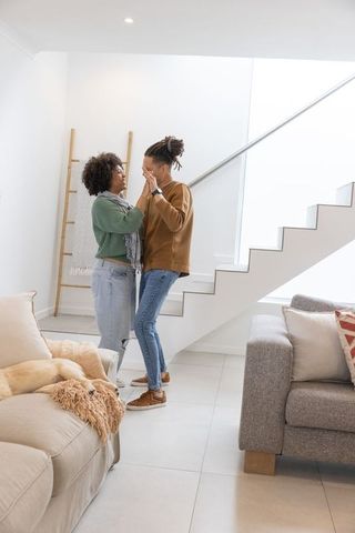 African american couple sharing tender moment near modern staircase in living room