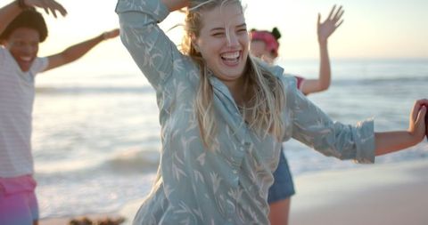 Group of friends enjoying fun day at beach in warm sunlight
