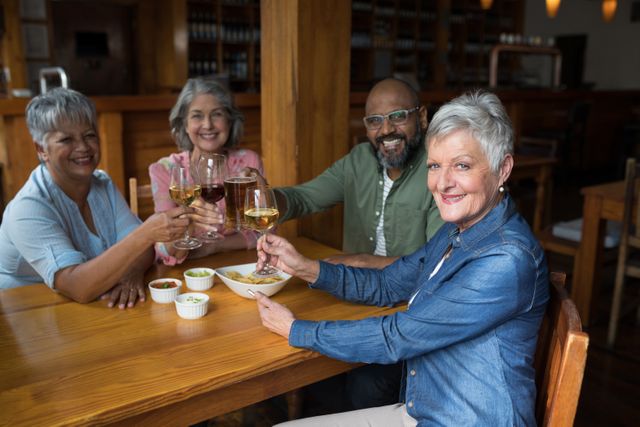 Group of senior friends enjoying wine and appetizers at a bar, smiling and toasting. Perfect for illustrating themes of friendship, socializing, leisure activities, and senior lifestyle. Ideal for use in advertisements, blogs, and articles related to senior living, social gatherings, and dining experiences.