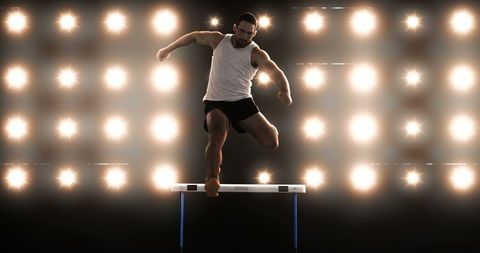 Athlete Training Over Hurdles Under Bright Stadium Lights