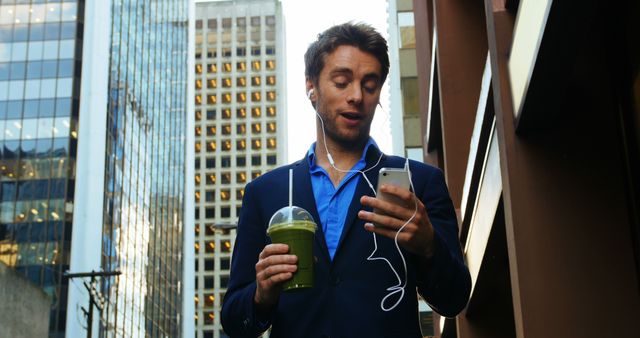 Businessman in Suit Walks Among City High-Rise Buildings with Smoothie and Smartphone - Download Free Stock Images Pikwizard.com