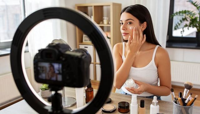 Beauty vlogger applying skincare cream for tutorial at home vanity with ring light