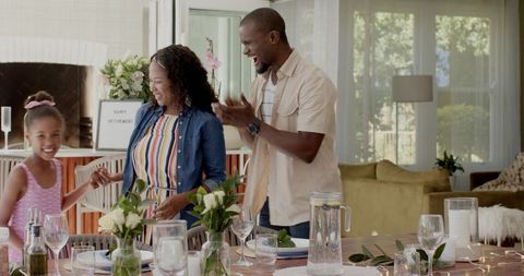 African American family celebrating retirement at sunlit dining table with daughter