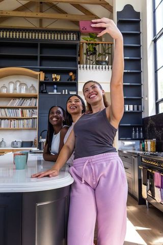 African american women taking selfie in bright modern farmhouse kitchen, smiling and posing