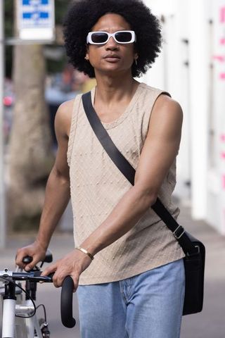 African american man walking pushing bicycle wearing white sunglasses urban commuter